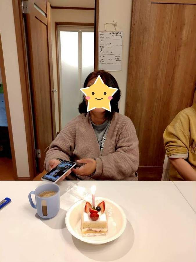 ろうそく付きのケーキを前に座る入居者さん