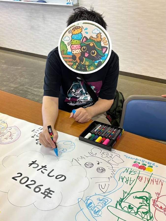 寄せ書きに絵を描くメンバーさん